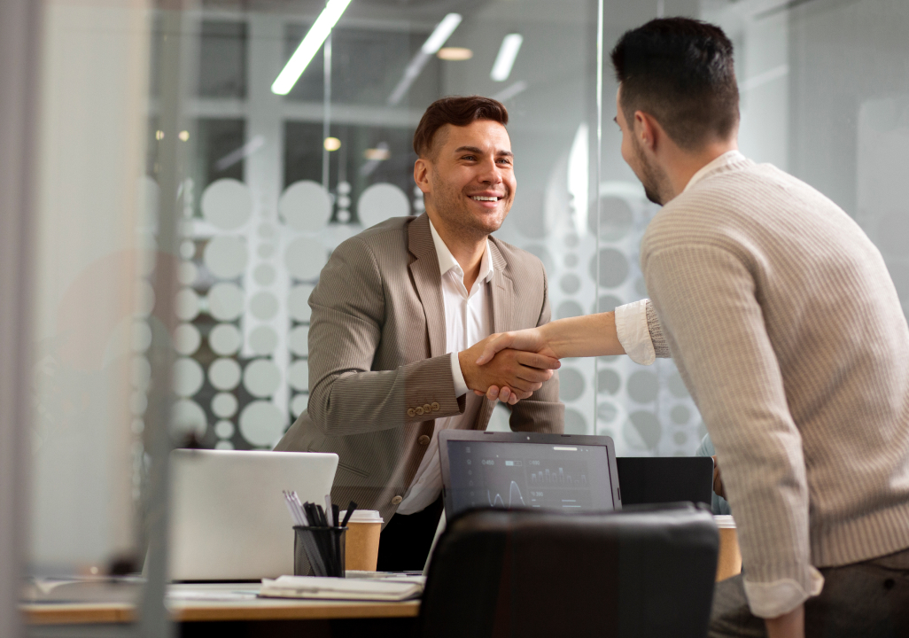 Two professionals shaking hands in an office representing a successful recruiting environment