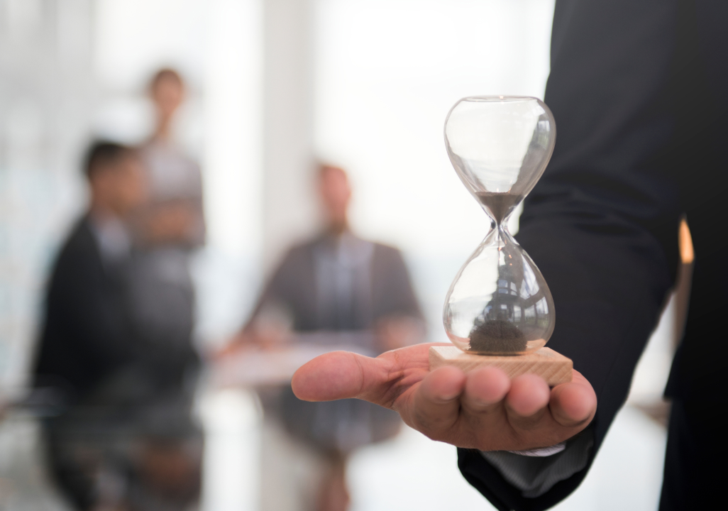 A businessman holding an hourglass in front of a group of qualified talent.