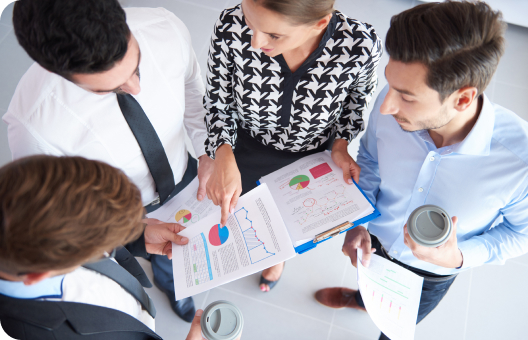 A group of four professionals collaborating, with graphic documents and data analysis in their hands.