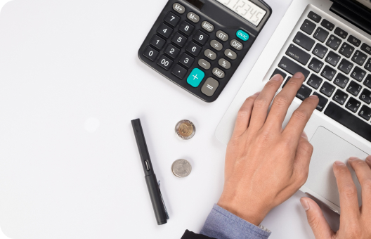 An executive recruiter typing on a laptop with a calculator and coins.