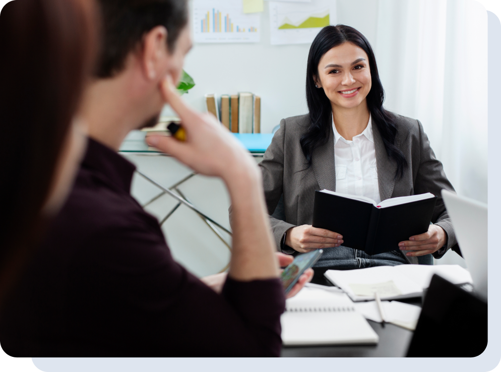 A man and a woman sitting at a desk talking to each other at a job interview.